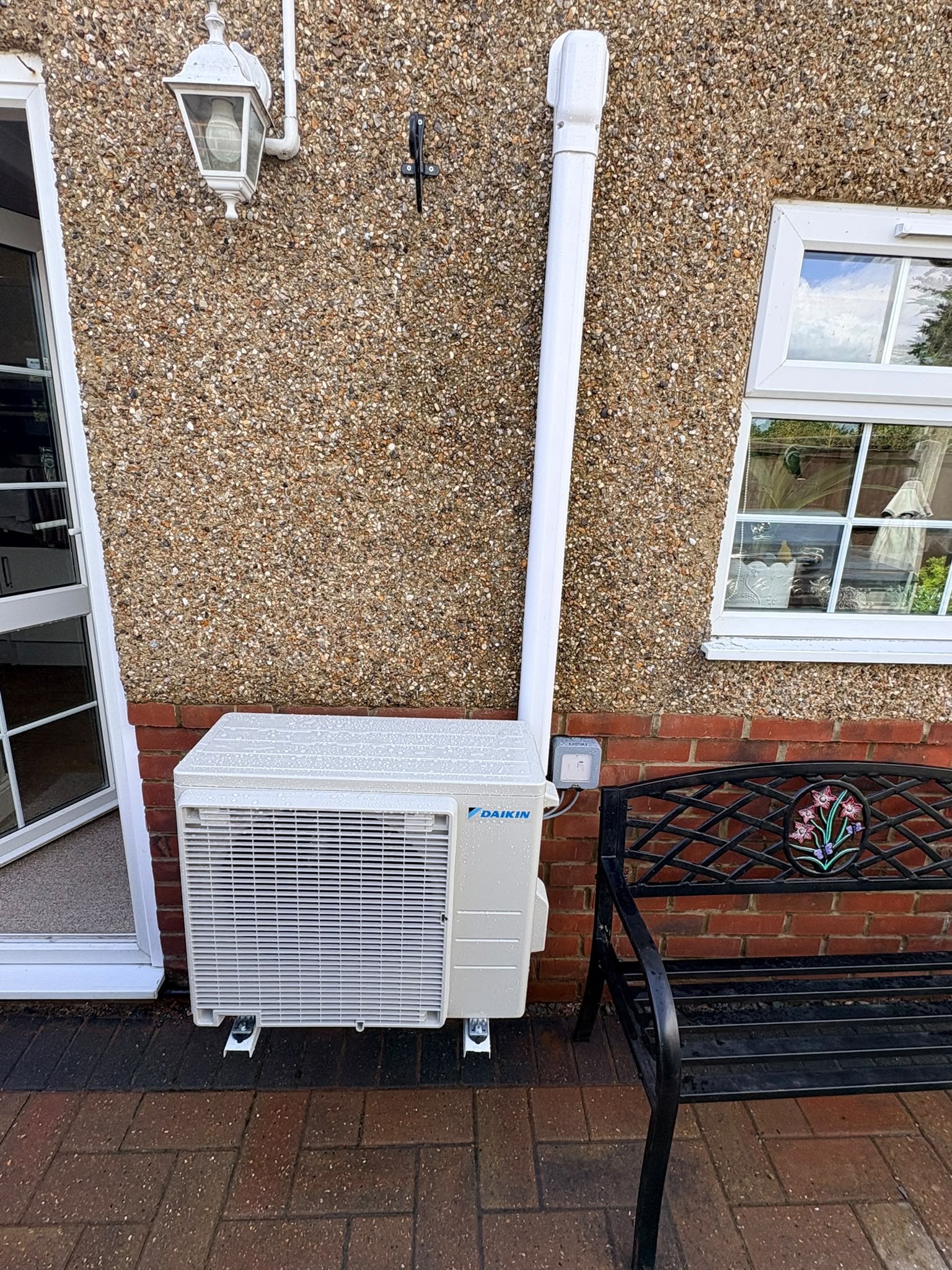 Outdoor condenser wall mounted on brackets clear of the paving